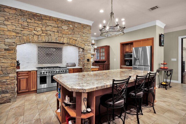 kitchen featuring crown molding, stainless steel appliances, light stone countertops, a kitchen island, and decorative backsplash