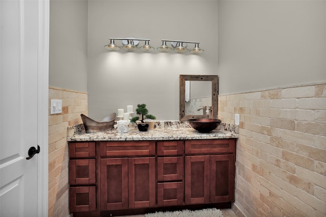 bathroom with brick wall, wainscoting, vanity, and tile walls