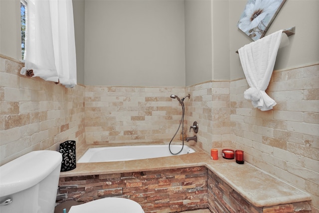 bathroom with wainscoting, a garden tub, tile walls, and toilet