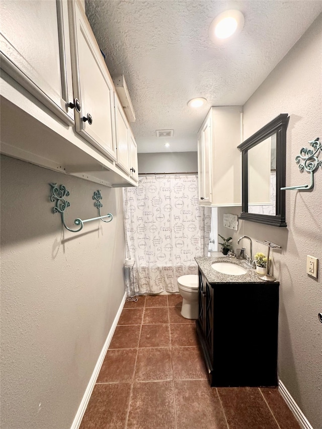 bathroom with toilet, a textured ceiling, tile patterned floors, and vanity