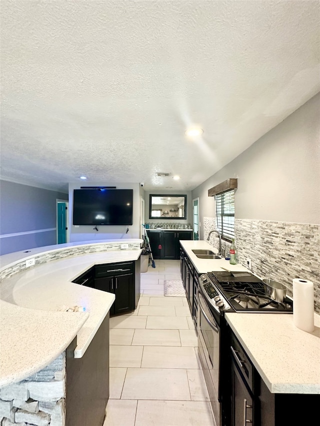 kitchen with double oven range, light stone countertops, sink, a textured ceiling, and light tile patterned flooring