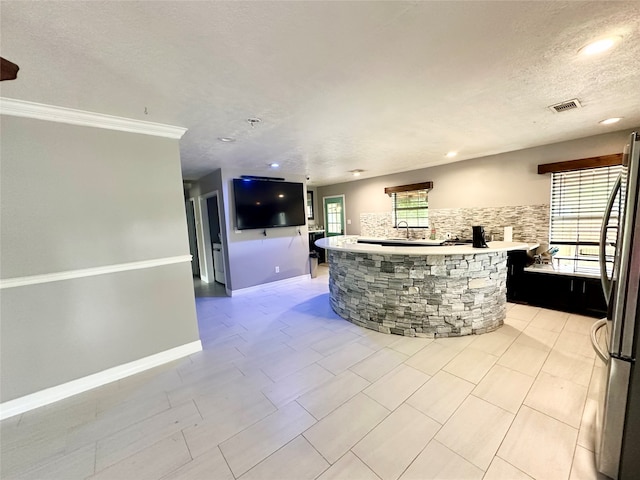 kitchen with stainless steel refrigerator, a textured ceiling, a center island, and light tile patterned flooring