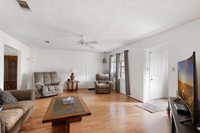 living room with a textured ceiling, light hardwood / wood-style floors, and ceiling fan