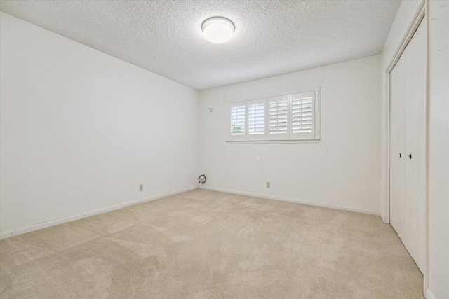 unfurnished bedroom featuring a closet, a textured ceiling, and light carpet