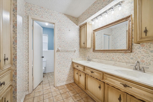 bathroom featuring toilet, a textured ceiling, tile patterned floors, and vanity