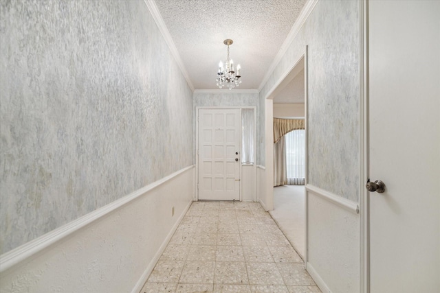 hall with a textured ceiling, a notable chandelier, and crown molding