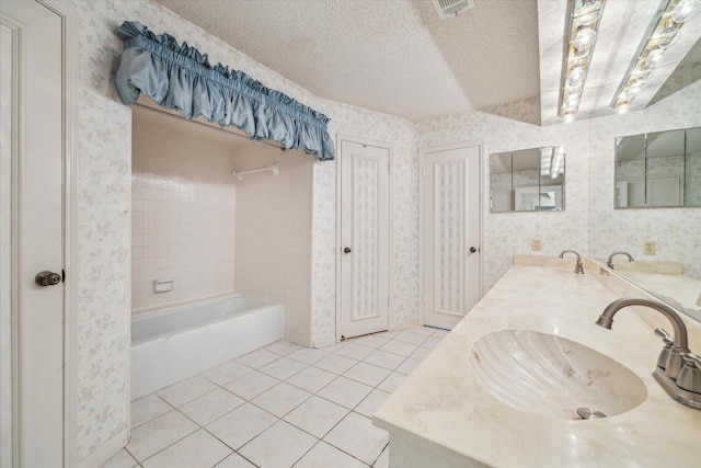 bathroom with a textured ceiling, vaulted ceiling, tiled shower / bath, tile patterned flooring, and vanity