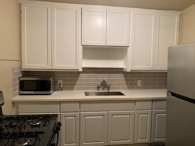 3205 Illinois St, Baytown, TX 77520 - kitchen featuring appliances with stainless steel finishes, white cabinetry, light countertops, and decorative backsplash