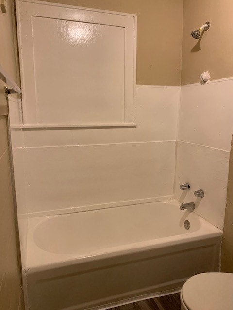 bathroom with bathing tub / shower combination, toilet, and wood-type flooring