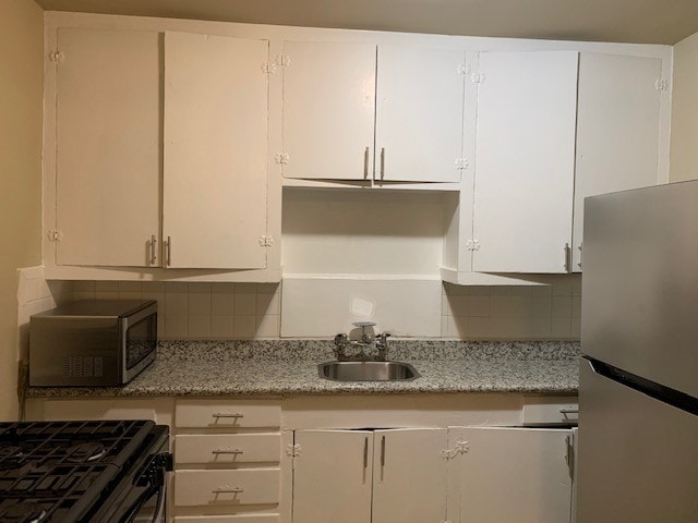 kitchen featuring appliances with stainless steel finishes, white cabinetry, and tasteful backsplash