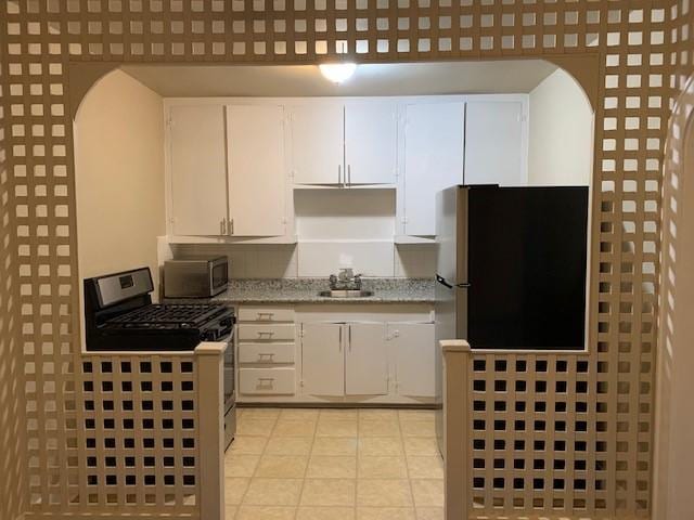 3205 Illinois St, Baytown, TX 77520 - kitchen with appliances with stainless steel finishes, white cabinetry, light tile patterned floors, and light stone counters