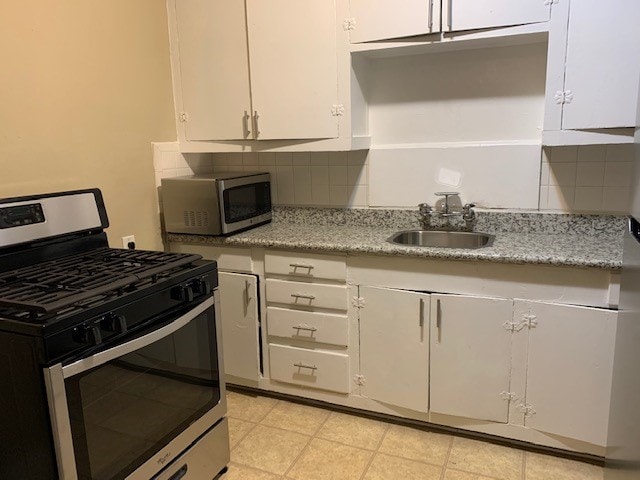 kitchen with stainless steel appliances, backsplash, sink, and white cabinetry