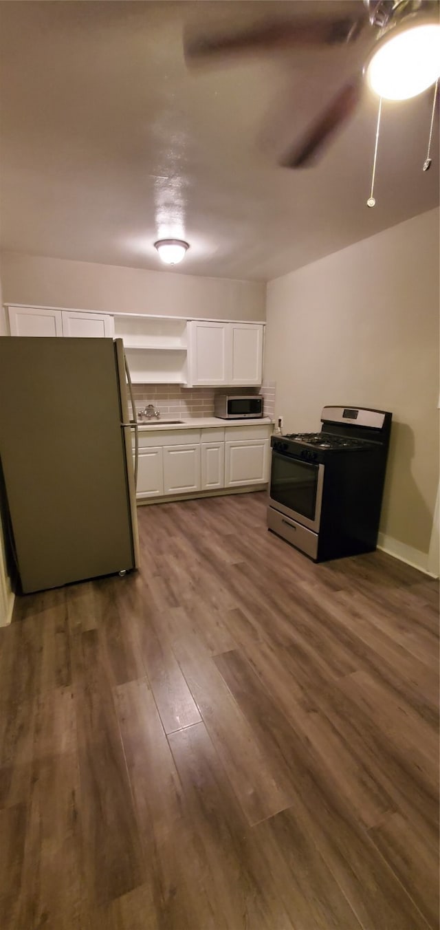 kitchen featuring dark wood-type flooring, white cabinets, stainless steel appliances, ceiling fan, and sink