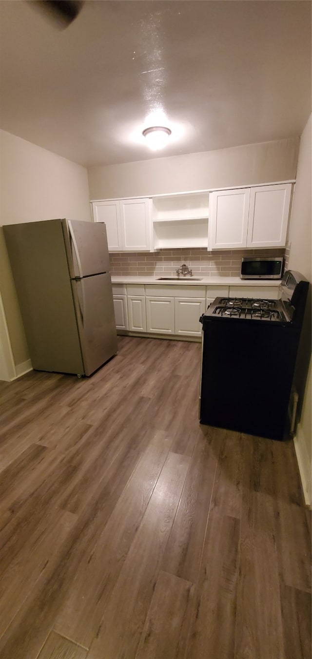 kitchen featuring white cabinets, sink, backsplash, appliances with stainless steel finishes, and dark hardwood / wood-style floors