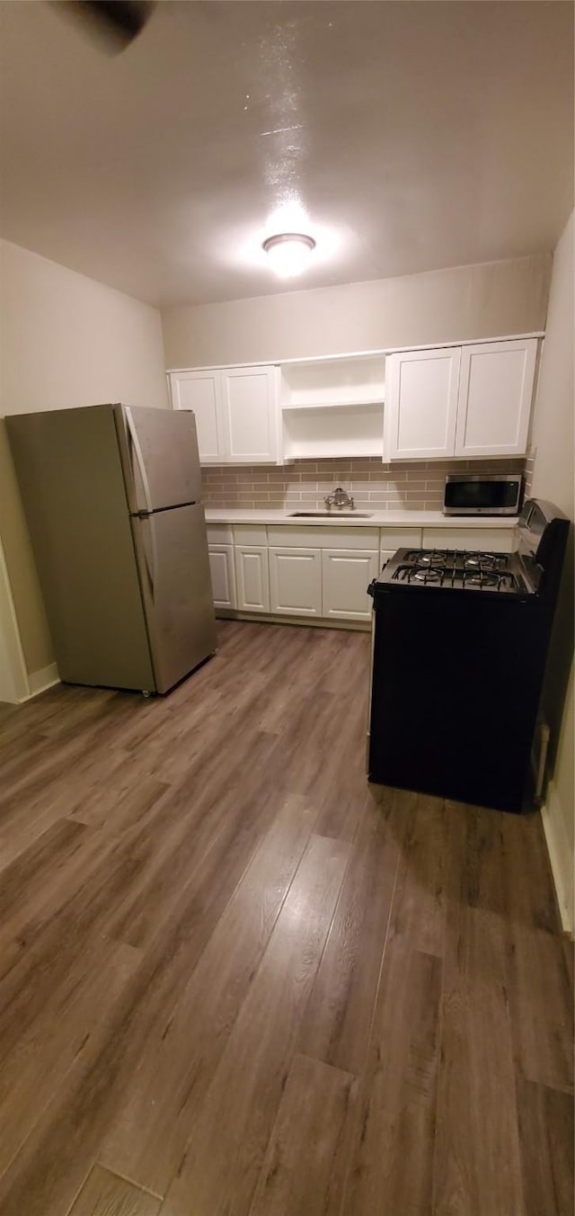 3205 Illinois St, Baytown, TX 77520 - kitchen with freestanding refrigerator, white cabinetry, tasteful backsplash, and wood finished floors