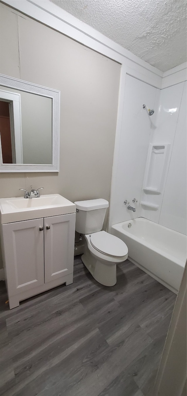 full bathroom featuring shower / washtub combination, vanity, a textured ceiling, toilet, and hardwood / wood-style floors