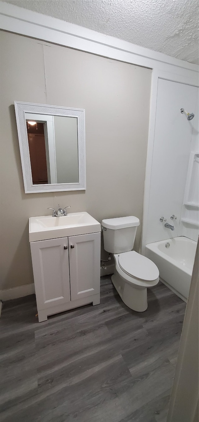 full bathroom featuring hardwood / wood-style floors, a textured ceiling, vanity, and toilet