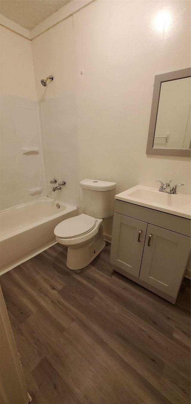 full bathroom with wood-type flooring, bathing tub / shower combination, vanity, and toilet