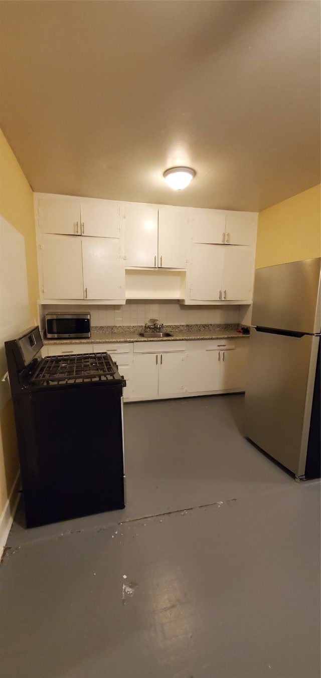 kitchen featuring sink, appliances with stainless steel finishes, concrete floors, and white cabinetry