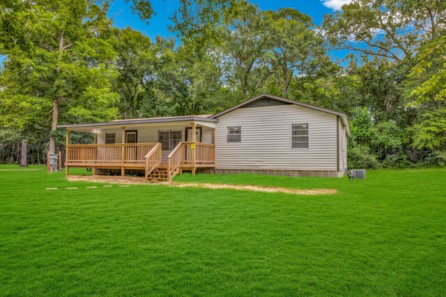 rear view of house featuring a wooden deck and a lawn