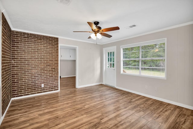 spare room with ornamental molding, brick wall, hardwood / wood-style floors, and ceiling fan