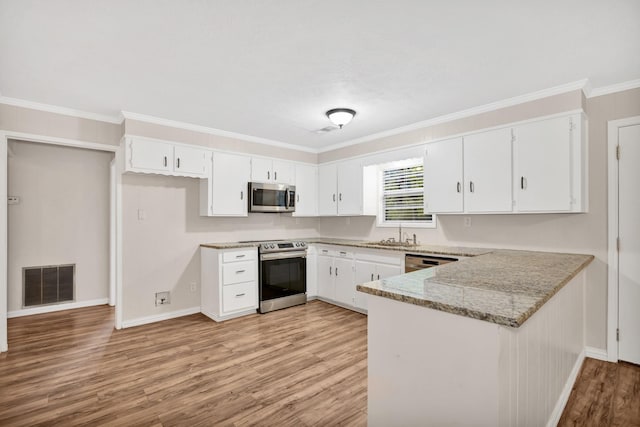 kitchen with stainless steel appliances, white cabinetry, light stone counters, and light hardwood / wood-style flooring