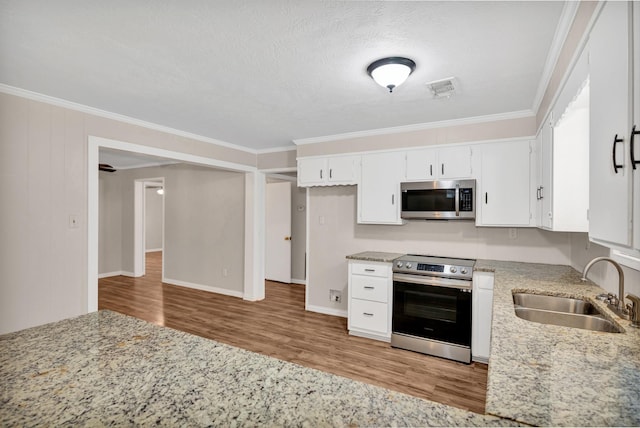 kitchen featuring sink, white cabinetry, stainless steel appliances, light stone counters, and ornamental molding