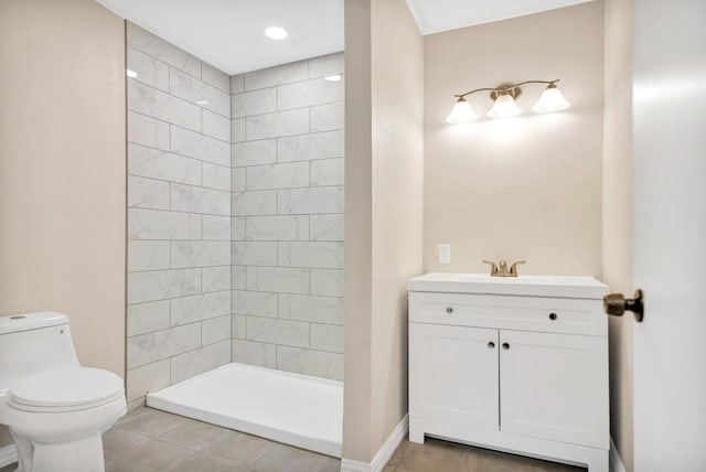 bathroom with tile patterned flooring, vanity, a tile shower, and toilet