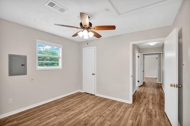 spare room featuring ceiling fan, electric panel, a textured ceiling, and light wood-type flooring