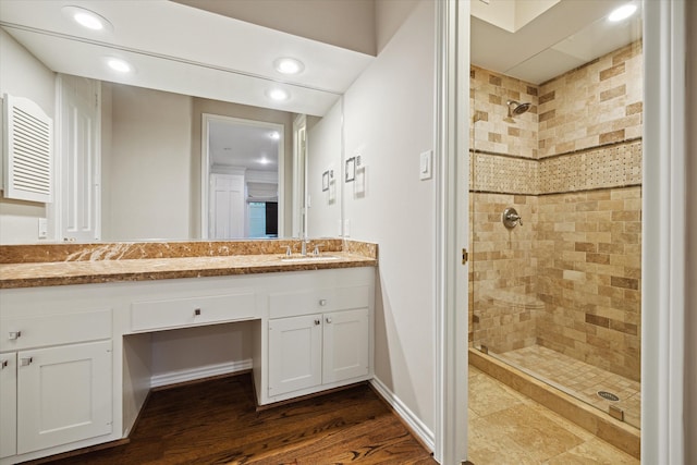 bathroom with tiled shower, vanity, and hardwood / wood-style flooring