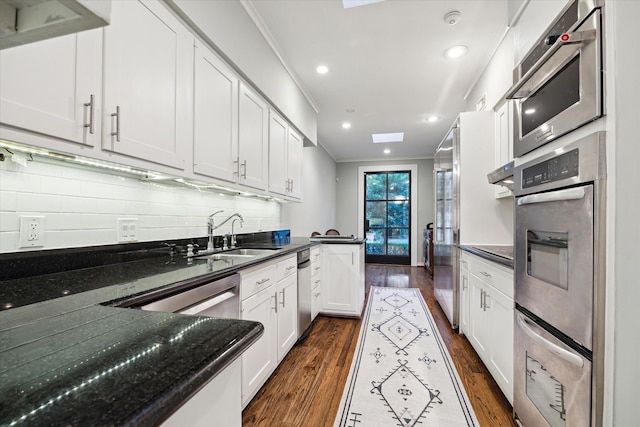 kitchen with white cabinetry, stainless steel appliances, decorative backsplash, ornamental molding, and dark hardwood / wood-style floors