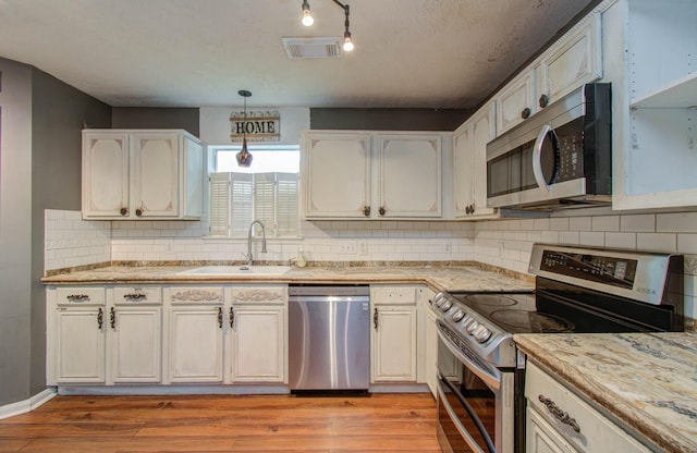 kitchen featuring light hardwood / wood-style floors, sink, hanging light fixtures, and appliances with stainless steel finishes