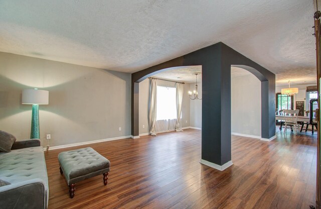 living room with dark hardwood / wood-style flooring, a textured ceiling, and a chandelier