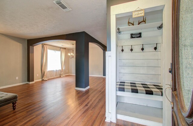 mudroom with a textured ceiling, hardwood / wood-style flooring, and an inviting chandelier