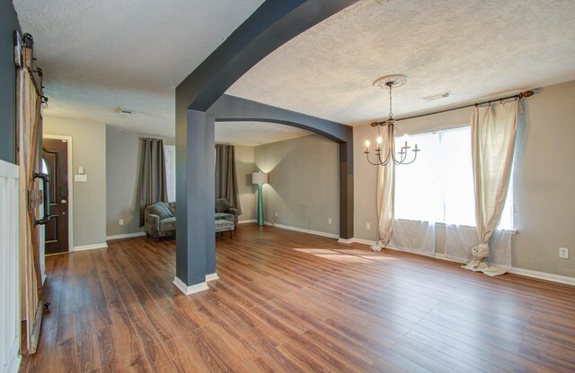 unfurnished dining area with a notable chandelier, dark hardwood / wood-style flooring, and a textured ceiling