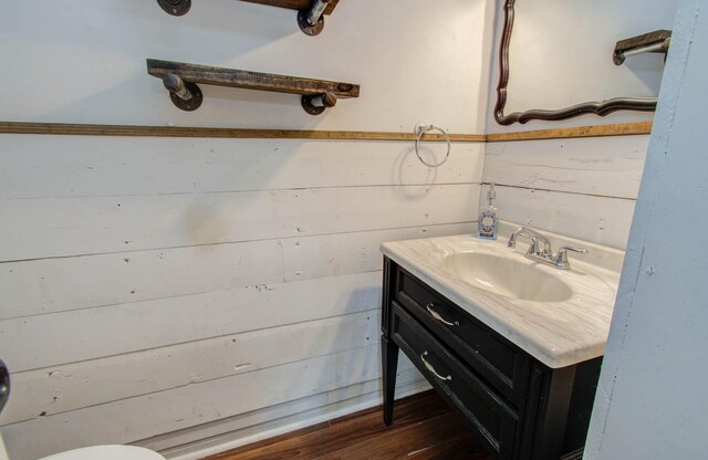 bathroom featuring hardwood / wood-style floors, vanity, and wooden walls