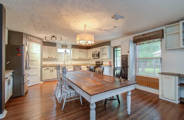 dining room featuring a textured ceiling, dark hardwood / wood-style floors, sink, and a notable chandelier