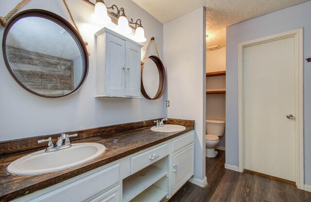 bathroom featuring vanity, wood-type flooring, a textured ceiling, and toilet