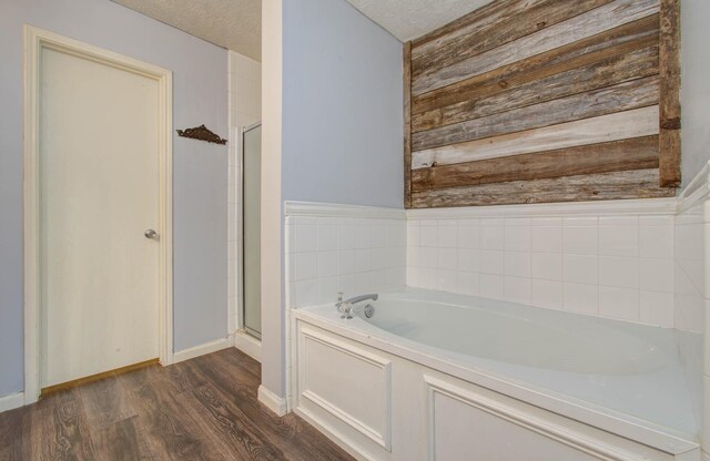 bathroom with a textured ceiling, hardwood / wood-style flooring, and independent shower and bath