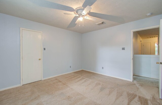 unfurnished room featuring a textured ceiling, ceiling fan, and light carpet