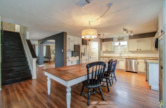 dining area featuring hardwood / wood-style floors, a chandelier, a textured ceiling, and sink