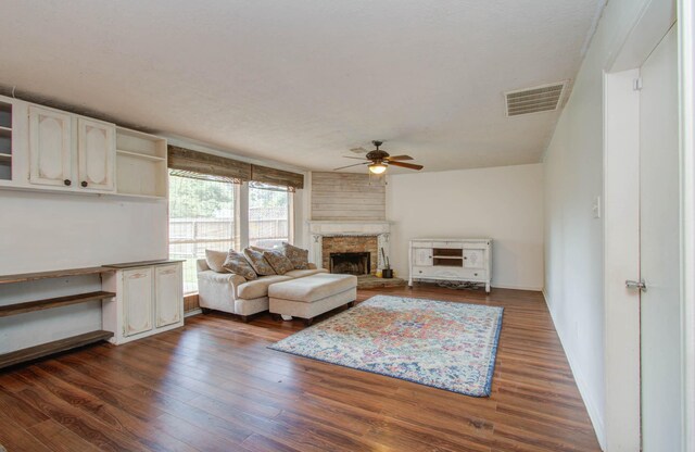 living room featuring ceiling fan, a fireplace, and dark wood-type flooring