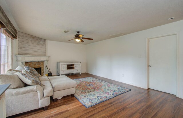 living room with hardwood / wood-style flooring, ceiling fan, and a fireplace