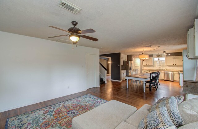 living room with a textured ceiling, ceiling fan, wood-type flooring, and sink