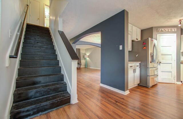 stairs featuring a textured ceiling and hardwood / wood-style flooring