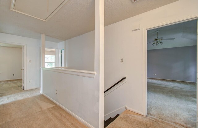 hallway featuring light carpet and a textured ceiling