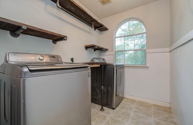 washroom with washer and clothes dryer, wood walls, and light tile patterned flooring