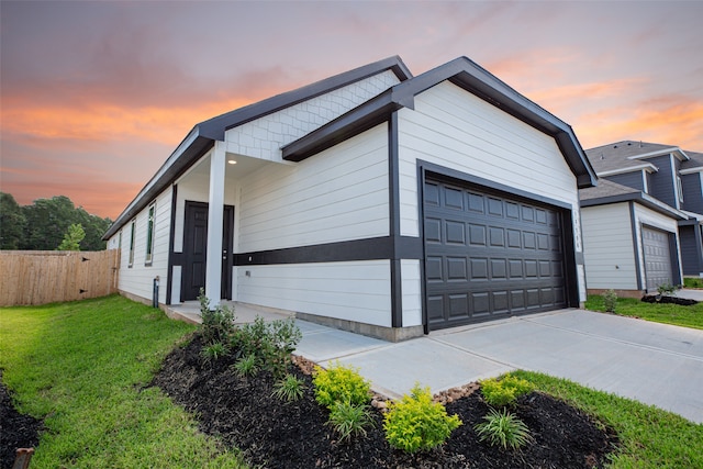 garage at dusk featuring a yard