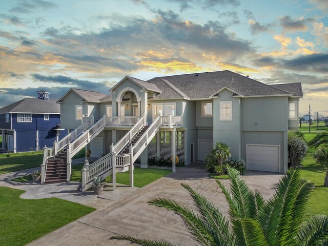 view of front of property featuring an attached garage, a shingled roof, driveway, stairway, and stucco siding