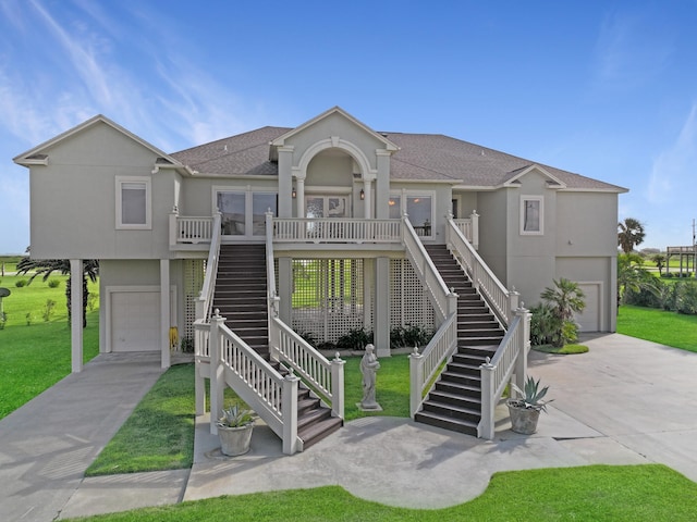 raised beach house featuring a garage, concrete driveway, stairway, and stucco siding